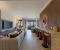 Tastefully furnished living room with a large Smart TV, bar, dining table, and balcony