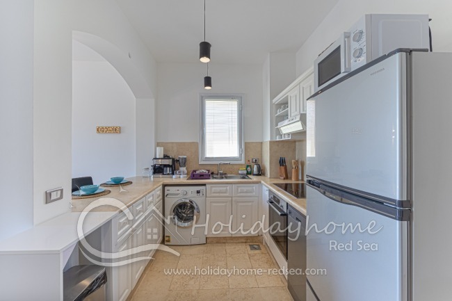 Fully equipped kitchen with stove, oven, large fridge with freezer, kettle, toaster, dishwasher, microwave, coffee machine, and washing machine